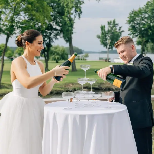 Bride and Groom pour champagne into glasses